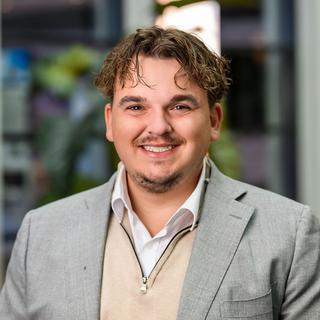a man in a suit and tie smiling for the camera